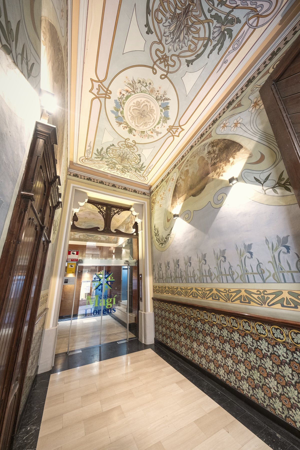 Vestíbulo modernista del edificio con el techo pintado y el zócalo de azulejo