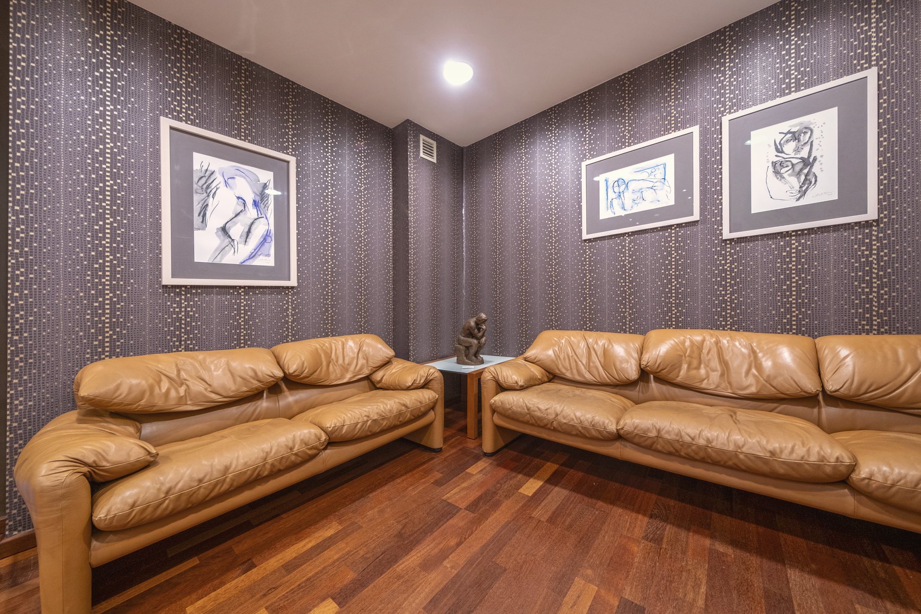 Sala de espera con sofás de piel y obra enmarcada